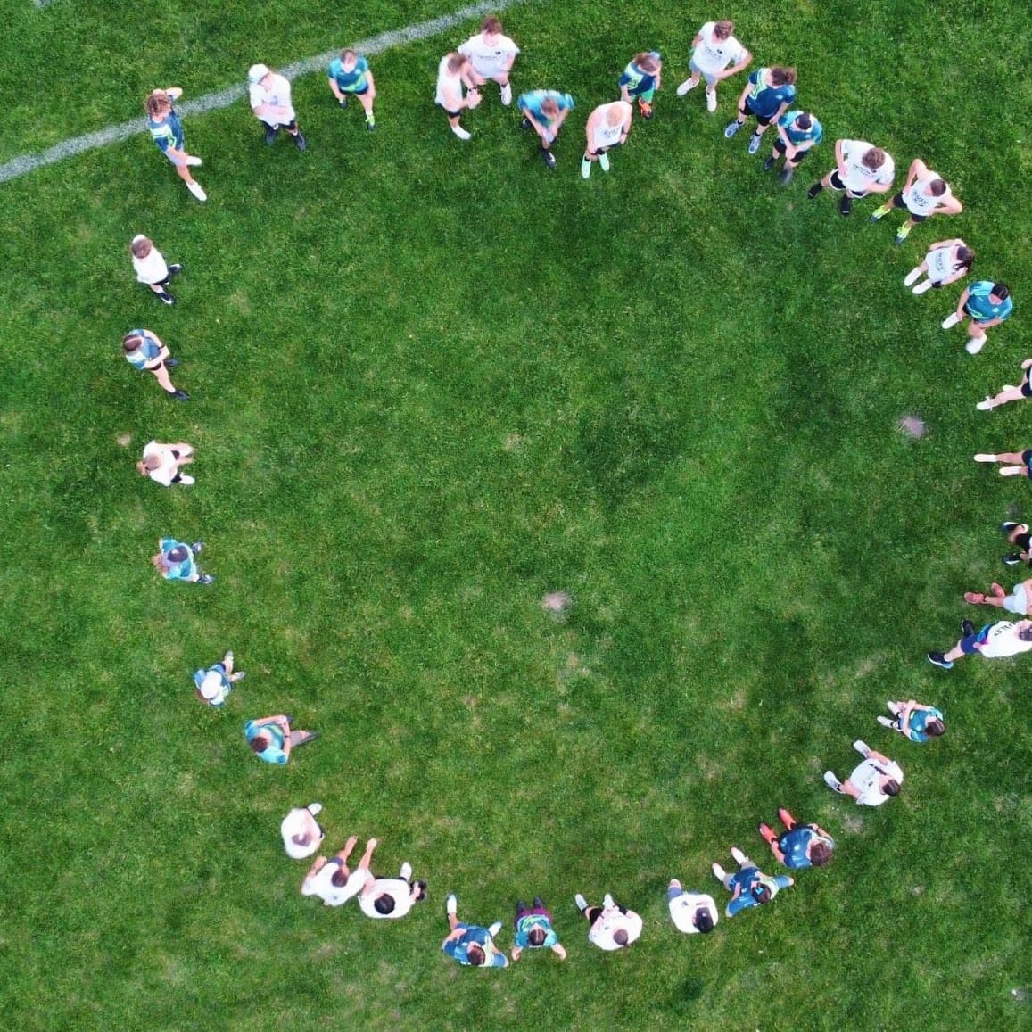 Overhead aerial of a circle of players on the grass.