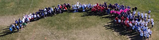 Aerial view of a large group arranged in an arc on a field.