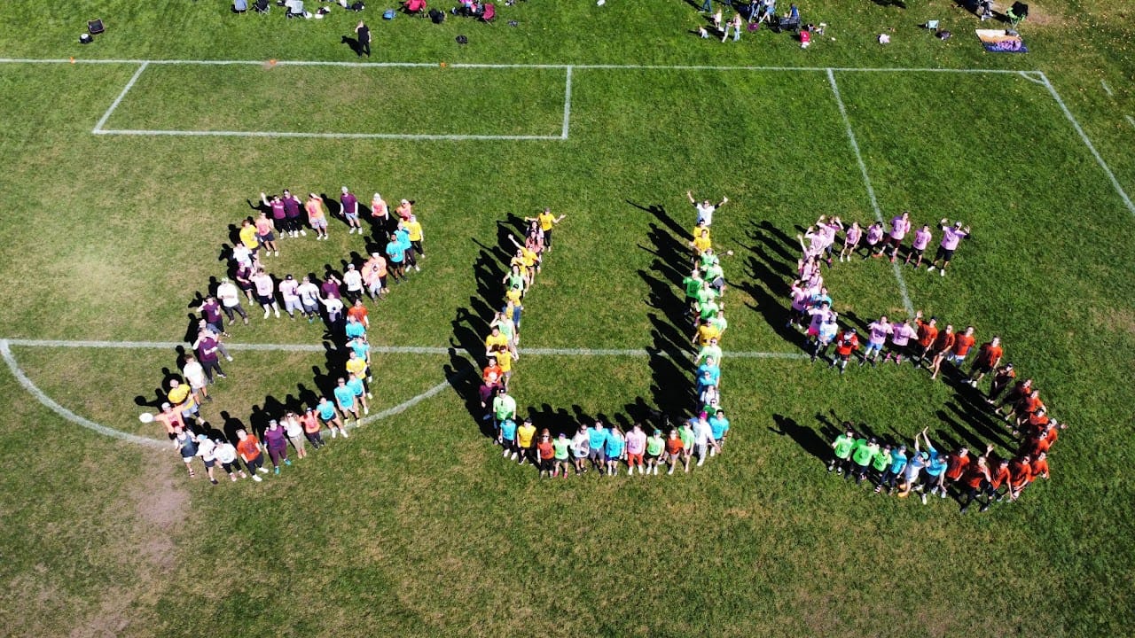 Aerial view of young players forming letters on a turf field.